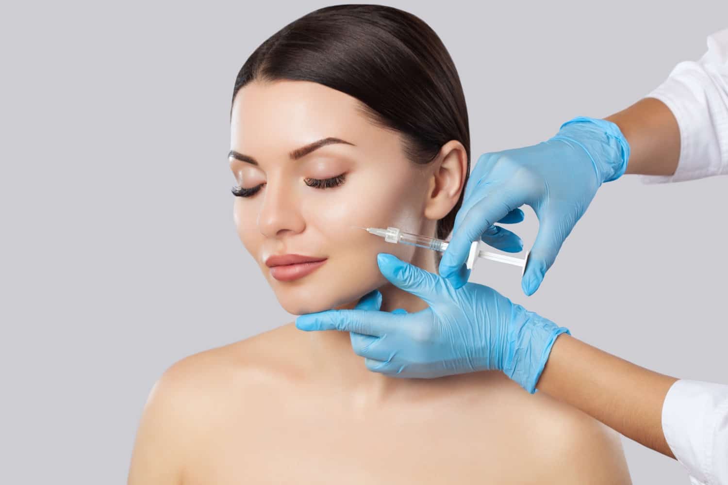 The doctor cosmetologist makes the Rejuvenating facial injections procedure for tightening and smoothing wrinkles on the face skin of a beautiful, young woman